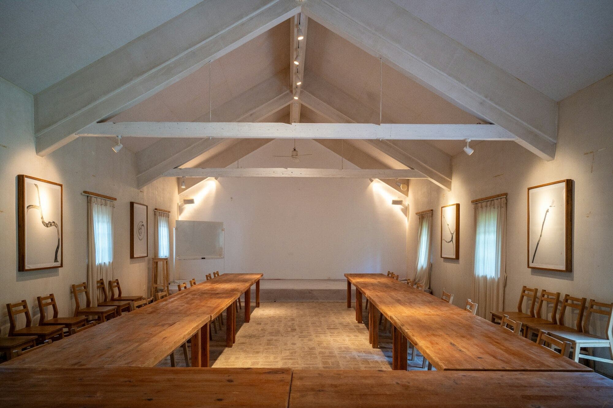 A bright room with a vaulted timber ceiling and long wooden tables set up for a workshop