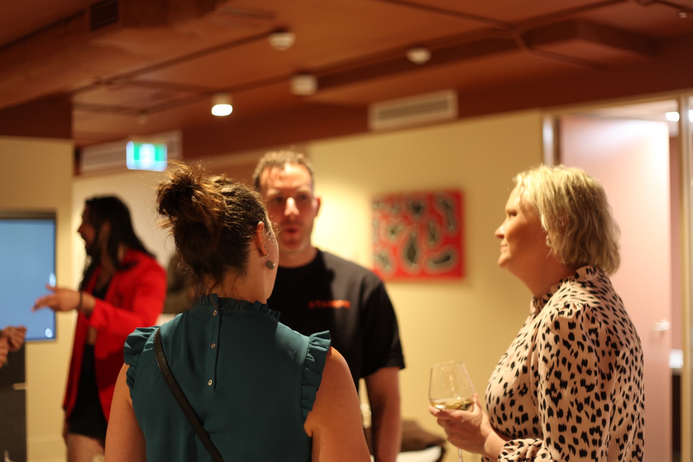 Guests talking beside a painting at a launch night