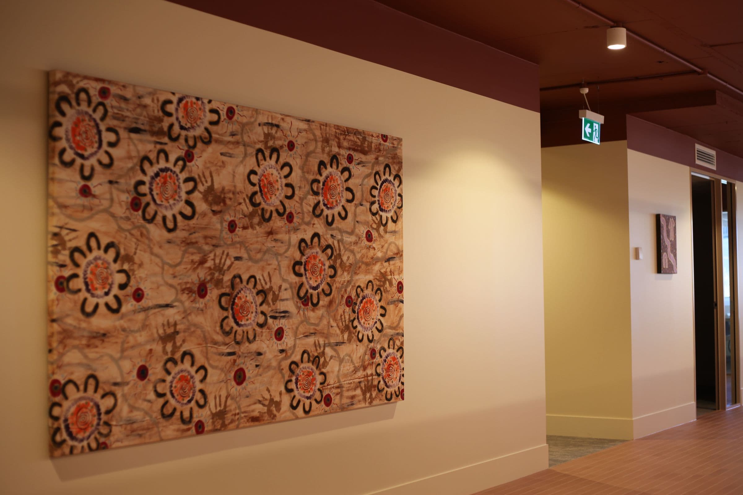 A large painting of ochre and red flowers in a corridor at Workspace by black vc