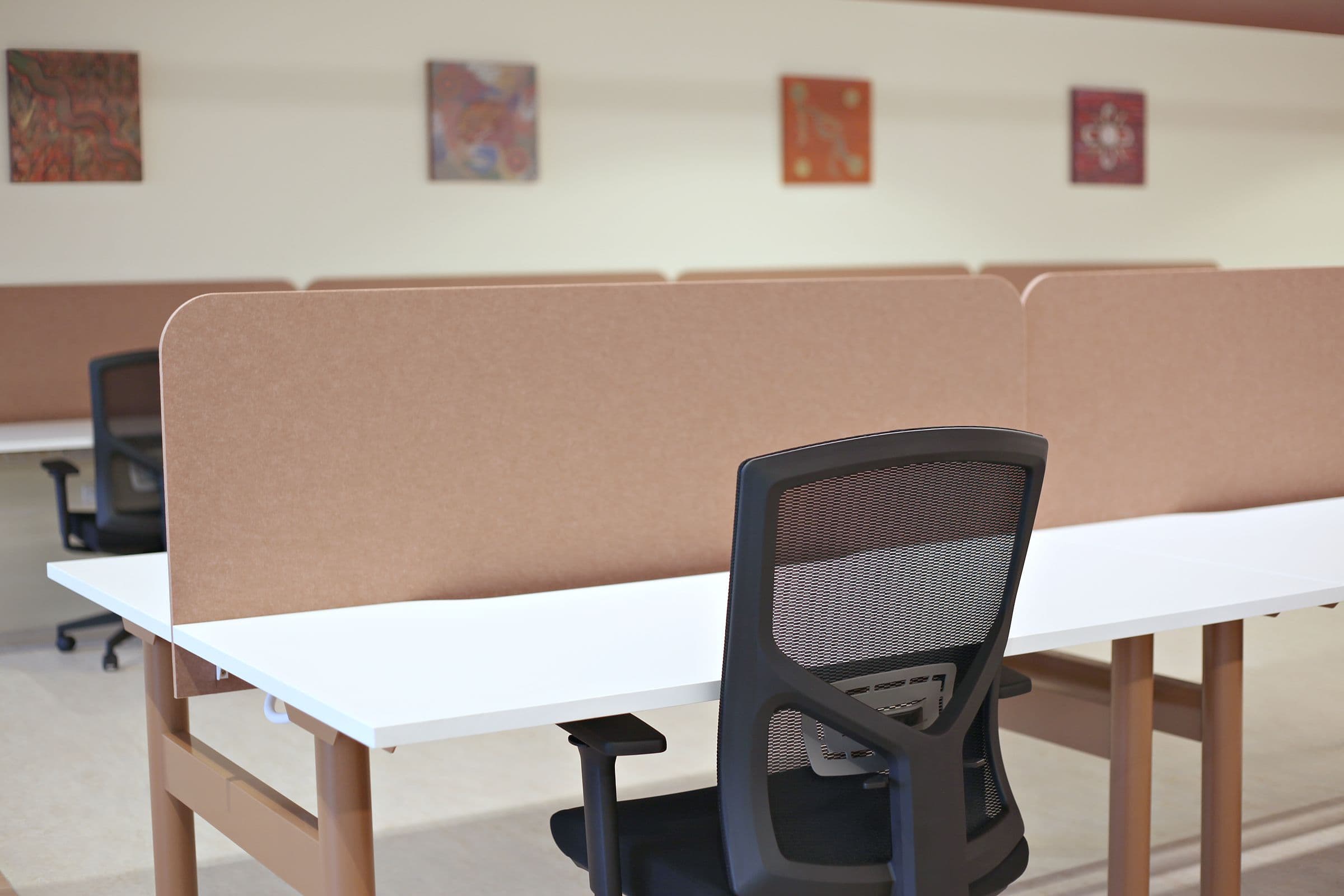 A dedicated desk with a task chair and screen divider