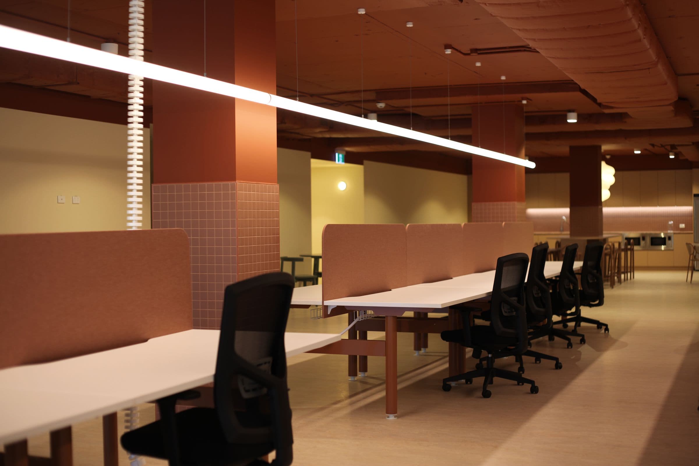 Open-plan desks with the kitchen and café beyond