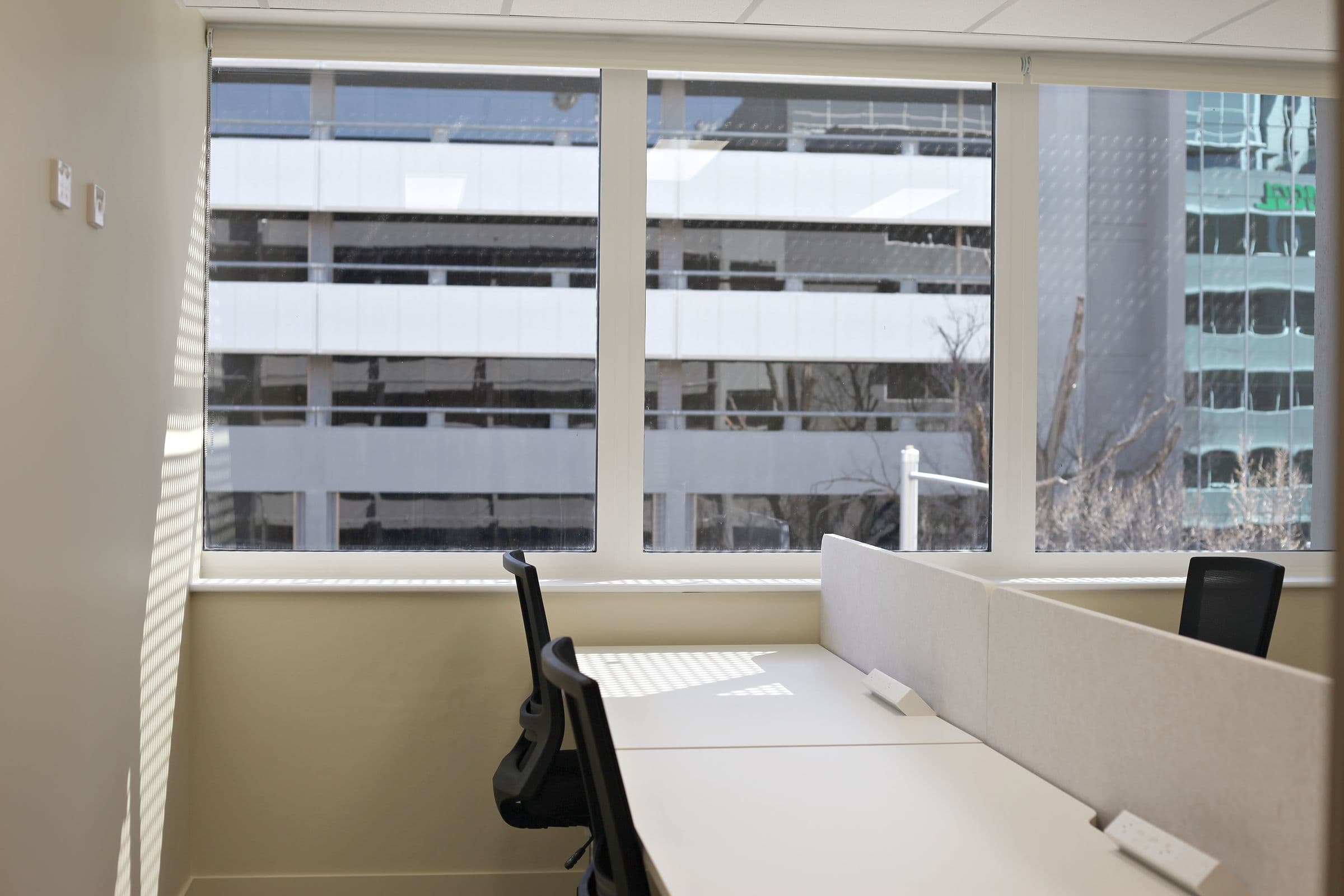A private office with desks by a wide window at Workspace by black vc