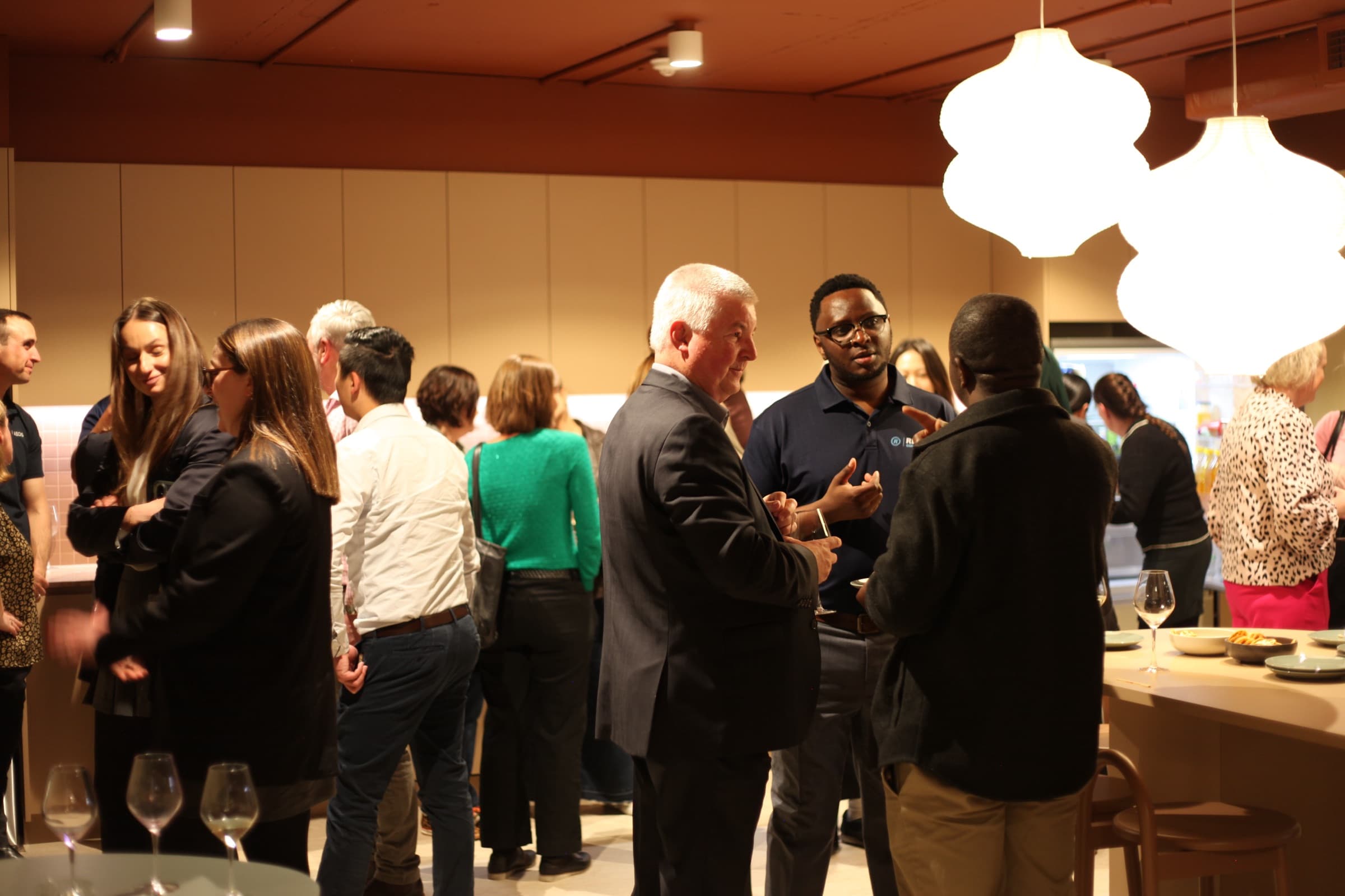 Guests talking under pendant lights at a launch night